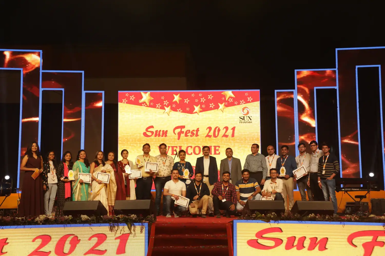 Man and woman speaking on stage at night with blue lighting